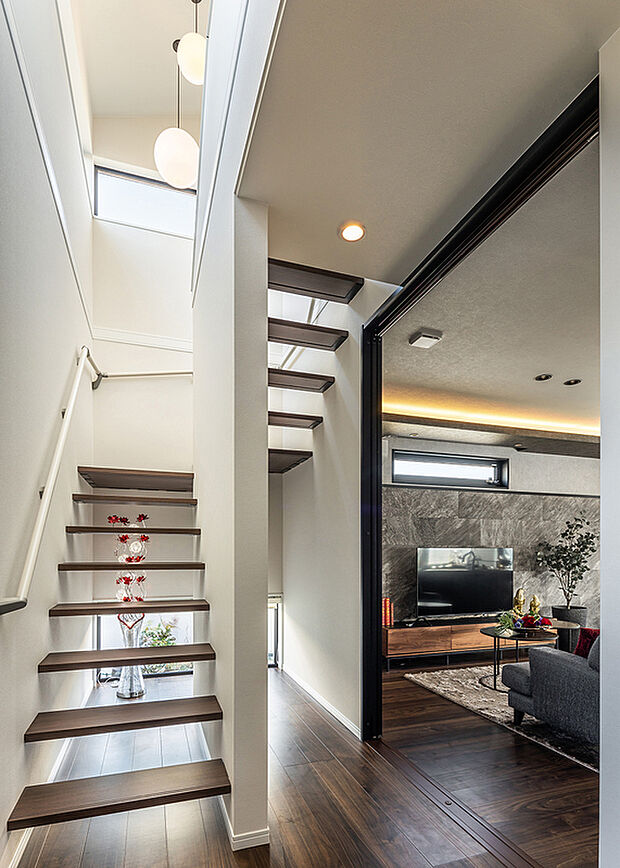 【玄関ホール】T-1/玄関を一歩入った先は、吹き抜けから注ぐ陽光と視線の先に広がる坪庭の緑が優しい空間。オープンな階段が空間に軽やかなリズムを生み、住まう人を心地よく包む、玉善品質を象徴する開放的な意匠です。