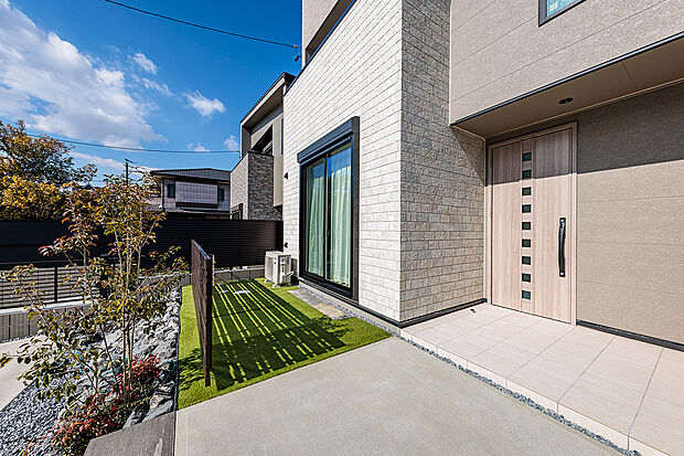 【外観】T-2/やわらかな陽光に包まれる南面の庭。リビングからつながる人工芝スペースに美しい植栽が彩りを添え、目隠しフェンスでプライバシーにも配慮。遊び場やくつろぎの場として活躍する心地よい庭空間です。