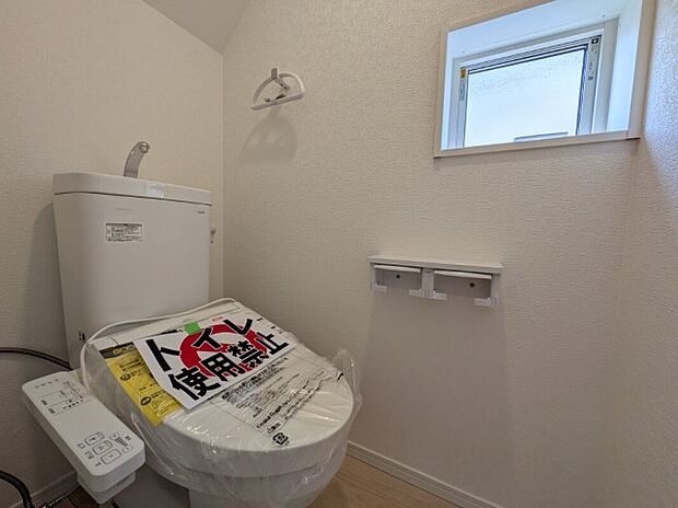 【トイレ】1号棟写真　白を基調とした、シンプルながらも落ち着くデザインです。洗浄機付き温水便座で機能性もばっちりです！毎日に欠かせないお手洗いだからこそ、ほっと落ち着く空間としての機能が重視されています。1階と2階に完備されているので、朝の忙しい時間帯に困ることはありません。
