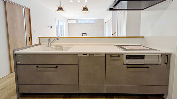 【【3号棟】キッチン／同仕様】木目の折り下げ天井と落ち着いた色合いのキッチンが調和し、上質で温かみのある空間に。