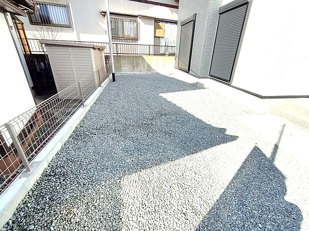 【庭スペース】砂利敷きで雑草が生えにくく、手入れも簡単な庭スペース。物置や自転車置き場など多用途に活用でき、外構も整えられた清潔感ある仕上がりで、防犯面にも配慮された安心の屋外空間です。