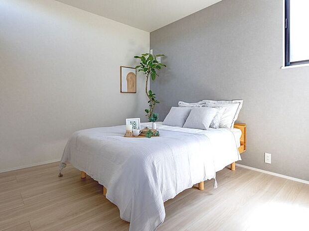 【リビング以外の居室】日差しが心地よい明るいベッドルーム。淡いグレーのアクセント壁が洗練された空間を演出します。木の温もり感じるフロアで癒やしのひとときを。心ゆくまでリラックスできる、あなただけの特別な安らぎの場所です。