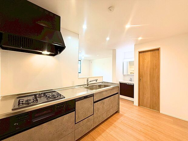 木目調のパネルが空間に溶け込む、清潔感あふれる対面キッチンです。家事の時短に欠かせない食洗機や、お料理の幅が広がる三口コンロを標準装備。