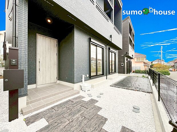 【洗練されたデザイン】モノトーンで統一されたアプローチには、お手入れしやすい白玉砂利の庭と飛び石を採用。プライバシーに配慮した設計で、都会的なセンスと快適な暮らしを両立しています。