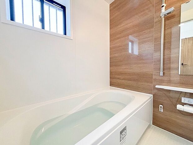 【ユニットバス】温かみのある木目調のアクセントパネルが心落ち着くリラックス空間を演出します。ゆったりとした浴槽に加え雨の日のお洗濯に重宝する浴室乾燥機も標準装備。また浴室に窓があるため換気もスムーズです。