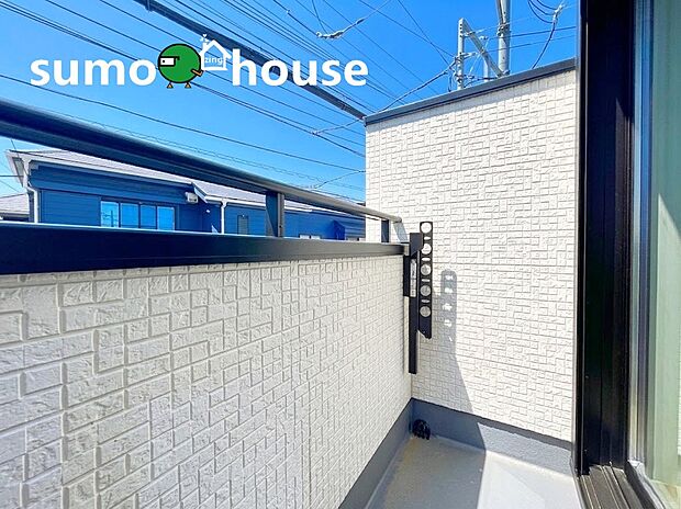 【落ち着いた住環境】抜けるような青空を仰ぐ、陽当たり良好な開放的バルコニーです 。外壁には清潔感のある白のアクセントパネルを採用し、明るく洗練された空間を演出 。便利な物干し金物付きで、毎日の洗濯もスムーズに行えます 。