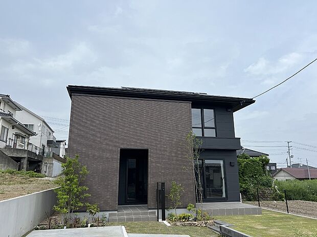 【現地外観写真】重厚感のある外観が印象的な住まい。庭には芝生が広がり、開放的な暮らしを楽しめます。