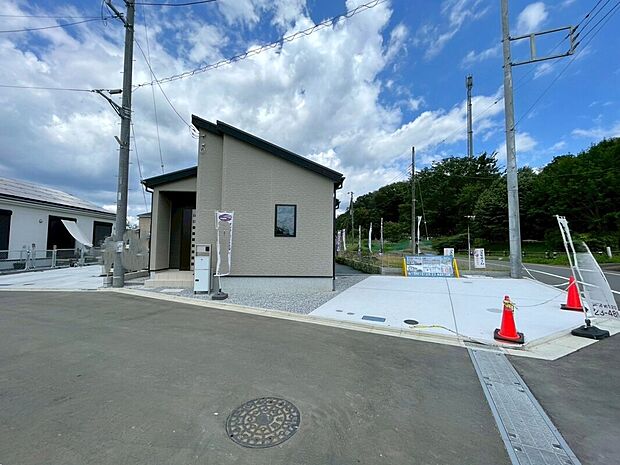 外観写真
平屋のモダンな外観。広いコンクリート敷きで駐車2台可能。
玄関横にポストとインターホンがあり、ベージュ系の外壁が緑に映える穏やかな住環境です。
