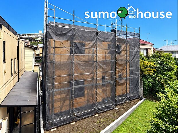 青空に映える建築中の新築邸宅。周囲の緑や落ち着いた住宅街の雰囲気に調和し、陽当り・通風ともに期待できる好立地です。完成前の今だからこそ、周辺環境や陽当り具合を現地でしっかりとご確認いただけます。