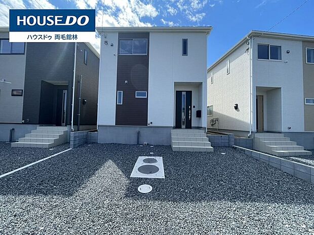 2号棟。ホワイトとダークブラウンの縦ラインが印象的な、スタイリッシュな外観デザイン。建物前にはゆとりある駐車スペースを確保し、車の出し入れもスムーズです。