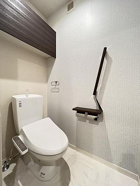 画像11:トイレには温水洗浄便座と、つかまりやすい手すり付の紙巻き器が設置されております。