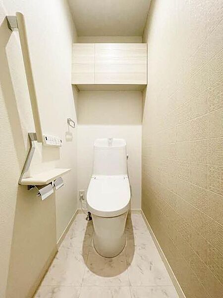 画像6:【トイレ】モロッカン柄のタイル調の壁紙が印象的な、シックな雰囲気のトイレ。上部吊戸棚、手摺、小物置きに使えるペーパーフォルダー天板があり、機能的にも充実しています。