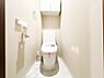トイレ：大理石調の床面と温かみのある上品なクロスが調和する、清潔感あふれるトイレ空間。手洗い一体型の便器で省スペースながら機能的であるほか、背部にはトイレットペーパーのストック等に重宝する吊戸棚付きです。