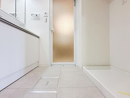 洗面化粧台と洗濯機置場、浴室を一カ所にまとめた機能的な水回り。脱衣や洗濯、身支度を効率よく行える動線が魅力です。落ち着いた色合いの床と白を基調にした、明るく清潔感のある空間です。
