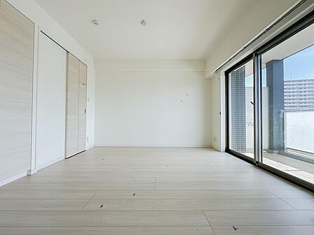 大きな開口部から陽光が差し込む、明るく開放的なリビング。淡い木目と白を基調とした内装は、さまざまな家具と調和します。ソファを置いて寛いだり、家族で会話を楽しんだりと、心地よい時間を育む空間です。