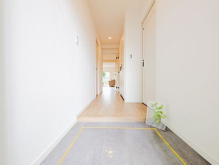 奥のリビングへと続く玄関。リビングドアが透明ガラスになっており、空間に奥行きと開放感をもたらします。