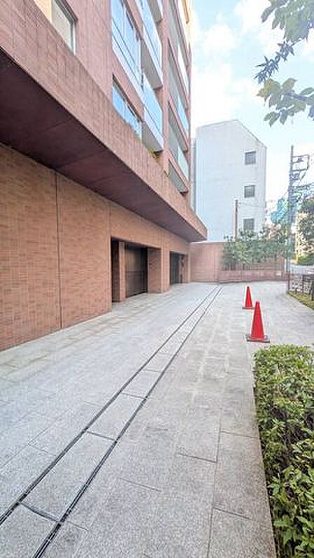 建物前の歩道状アプローチは、レンガ調の外壁に沿って続く落ち着いた空間。植栽も見られ、帰宅時に街中から住まいへ気持ちを切り替えられます!