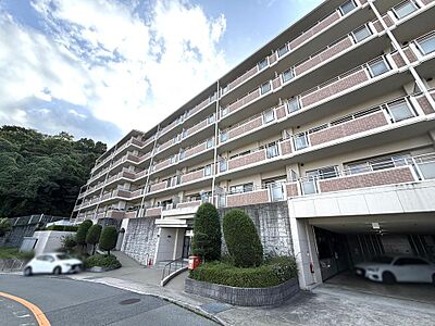 外観：自然豊かな住環境が魅力のマンション。傾斜地に建てられ、地下駐車場も完備。開放感あるバルコニーが各住戸に設けられています。