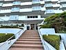 外観：緑に囲まれたエントランスが印象的なマンション。開放感あるバルコニーが連なり、豊かな住空間を予感させます。