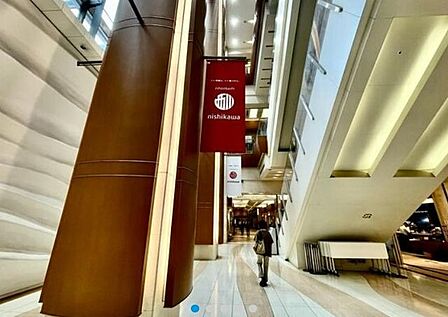 COREDO日本橋 吹き抜け構造を取り入れた開放的なデザインの施設内には、木目調の大柱や間接照明が配置されており、足元にはデザイン性の高いタイル敷きの通路がまっすぐに続いています。 1010m
