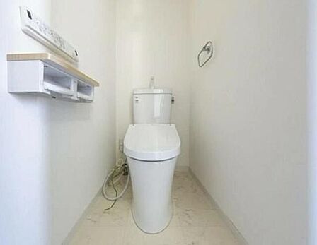 白を基調とした清潔感のあるトイレには、手洗い付きタンクや温水洗浄便座のリモコン、小物が置けるカウンターが付いた2連ペーパーホルダーやタオル掛けなどの設備が整っています。
