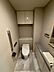 トイレ：温水洗浄機能付きのトイレには、手洗いボウルを備えたカウンターや鏡、立ち座りをサポートする手すりが設置されており、上部にはペーパーなどのストックに便利な吊戸棚収納も確保されています。