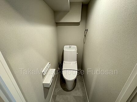 シックな石目調床とクロスが上質なトイレ空間。温水洗浄便座や便利な棚付きリモコンを完備