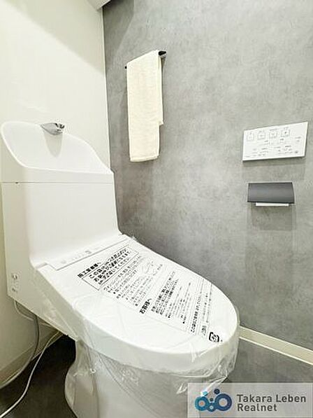 ウォシュレット機能付きのトイレは壁掛けリモコンの上位グレードを採用。便座がスッキリした印象となり、限られた空間を広く見せる効果があります。