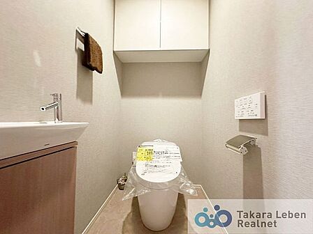 ウォシュレット機能付きのトイレは壁掛けリモコンの上位グレードを採用。便座がスッキリした印象となり、限られた空間を広く見せる効果があります。