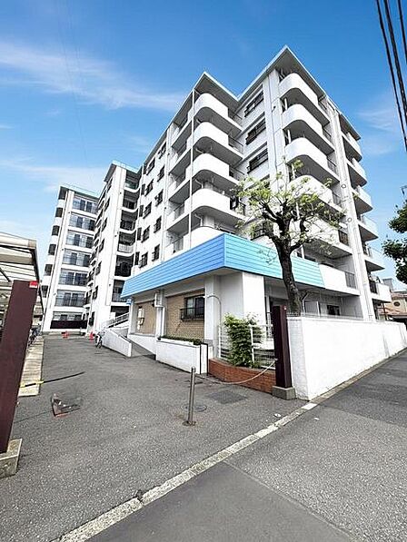青い屋根がアクセントとなる、緑に囲まれた穏やかな低層集合住宅。