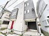 外観：洗練されたモノトーンの外観に鮮やかな赤い扉がアクセントを添える個性的な佇まい
