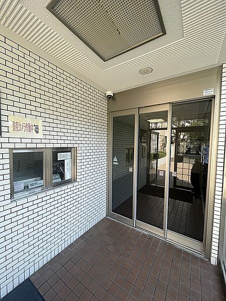 防犯カメラ作動中の表示があるエントランスは、日々の暮らしに配慮した設計です。自動ドアでスムーズな出入りをサポートします。