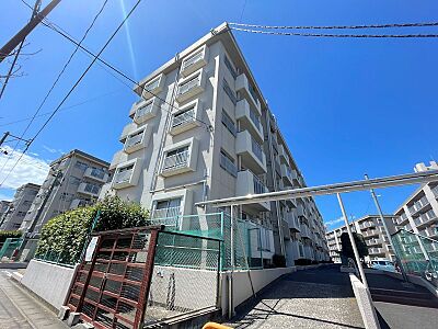 外観：広々とした敷地に佇むマンション。駐車場も整備されており、快適なカーライフをサポートします。青空が広がる開放的な環境で、新生活をスタートしませんか。