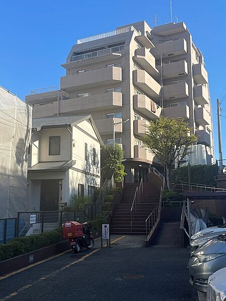 青空の下、風格ある外観が目を引くマンション。高台に位置し、開放感あふれる暮らしを予感させます。アプローチの階段が、住まいの趣を高めます。