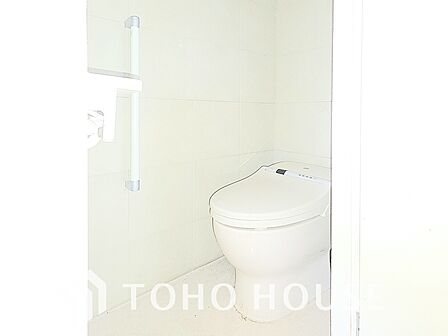 白を基調とした、清潔感あふれるトイレです。温水洗浄便座が完備されており、快適に利用できます。上部には収納棚も設置されており、トイレットペーパーなどをストックするのに便利です。