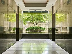 共用部の一角とは思えないほど、贅沢にデザインされたエレベーターホール。全面ガラスの向こうに広がるシンボルツリーと石積みの壁が、訪れたゲストを格調高く出迎えます。