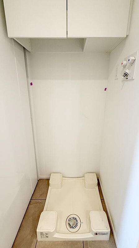 上部吊戸棚付きの洗濯機スペース。洗剤や掃除用品までまとめて収納でき、空間を有効活用できます。室内(2026年7月)撮影