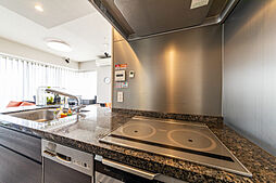 【天然石の煌めき】開放的なフルフラットキッチンが主役。上質な御影石の天板や充実の設備が、日々の料理を特別な時間に。リビングの大きな窓から光が溢れ、洗面室まで統一された美学が宿る、都心の洗練された邸宅。
