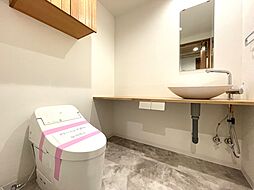 すっきりとしたデザインのウォシュレット付きトイレです。室内は天然無垢材の温もりを感じる落ち着いた上質な空間です。吊戸棚も設置されていて、ミラー付の便利な専用手洗いスペースも付いています。