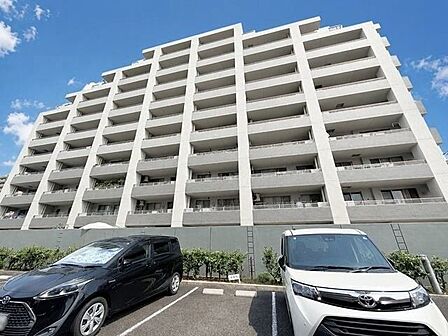 青空に映えるスタイリッシュなマンション外観。開放感のある佇まいと、整えられた植栽が印象的です。
