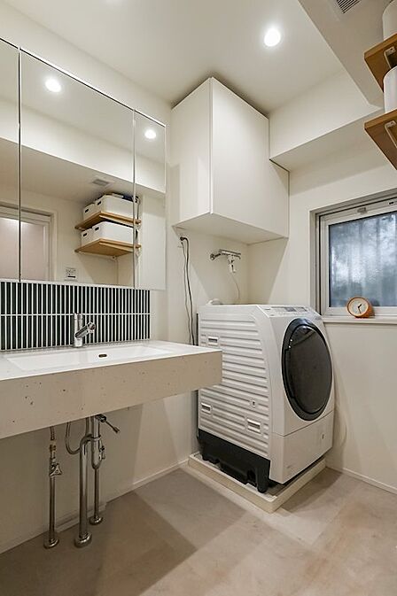 モノクロのテラゾー柄の洗面台。壁の一部には縦長のグリーンタイルを使用。