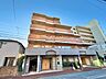 外観：エントランス前にバス停がありお出かけにも便利な立地。緑豊かな植栽が整然と彩りを添えています。