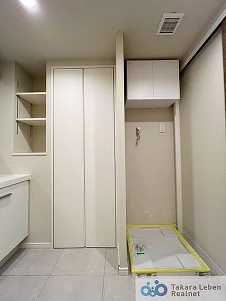 洗濯機置場。収納棚が設置されている為、洗剤類の収納場所としてお使いいただけます。