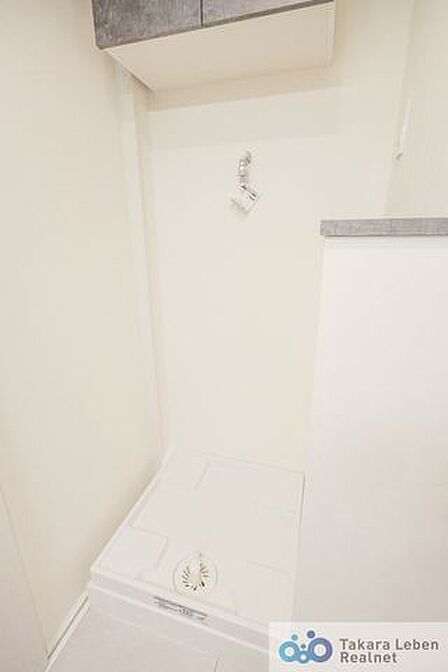 洗濯機置場。収納棚が設置されている為、洗剤類の収納場所としてお使いいただけます。