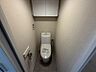 トイレ：温水洗浄便座と上部収納を備えたトイレ空間。落ち着いた色合いの壁紙が清潔感を演出します。