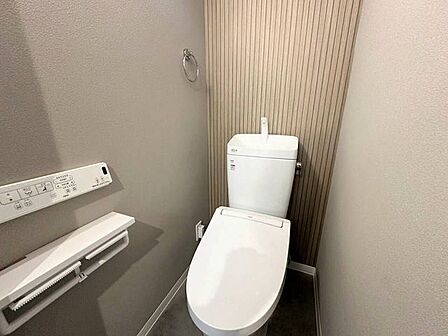 背面の木目調アクセントクロスが目を引く、ナチュラルテイストの洗練されたトイレ空間。