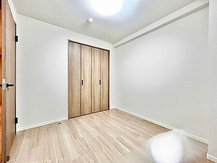 ナチュラルな木目調のクローゼット扉が目を惹く明るい洋室!白で統一された壁面と綺麗な木目調フロアが心地よい空間を演出します。大型収納付きで衣類や荷物を綺麗に収められ、快適にお過ごしいただけます。