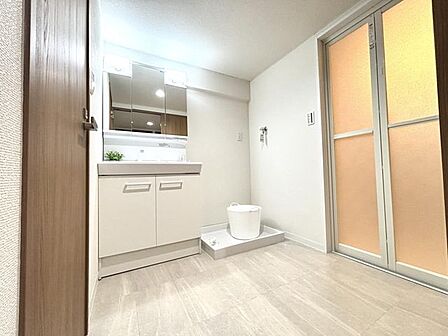 【洗面】便利な三面鏡の洗面化粧台を備えた、白を基調とする明るく綺麗な脱衣室です。