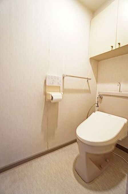 【トイレ】ホワイトを基調としたシンプルな内装です。上部には棚が設置されており、トイレットペーパーや掃除用具などをまとめて収納可能です。/2026年7月撮影