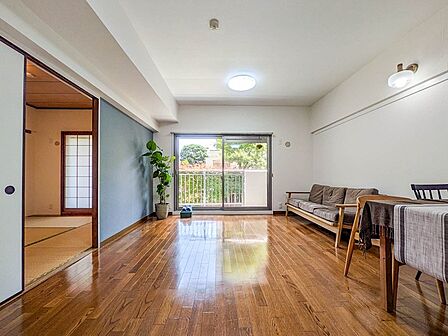 窓外に緑を望む、開放感のある明るいリビング。和室と隣接しており、扉を開放すればより広々と活用できます。